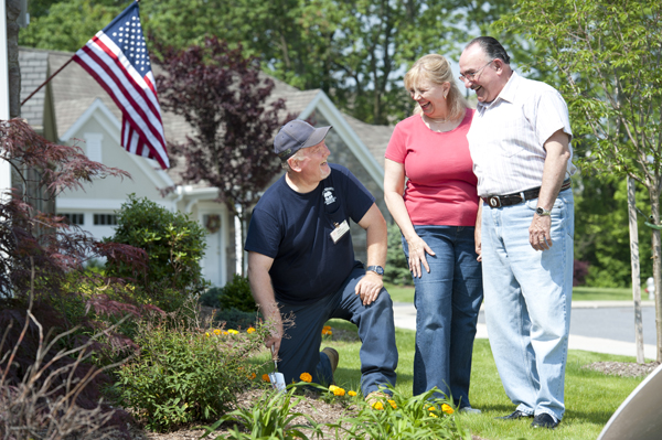 Couple talking to a man working in his garden