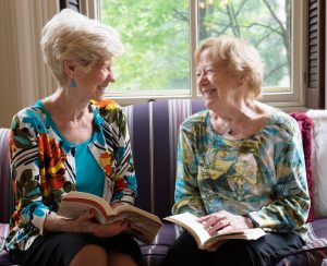 Two women smiling and reading books