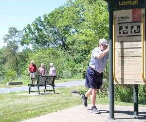 Senior residents walking along the rail trail and using the exercise station.