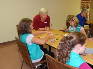 Cornwall Manor resident Barb Tonzi gives instructions on attaching a button