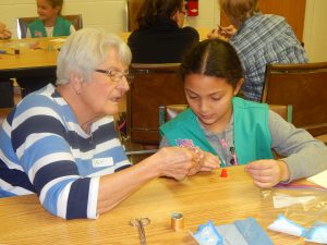 Resident Patricia Walter shows Girl Scout Eliani Cruz how to thread a needle