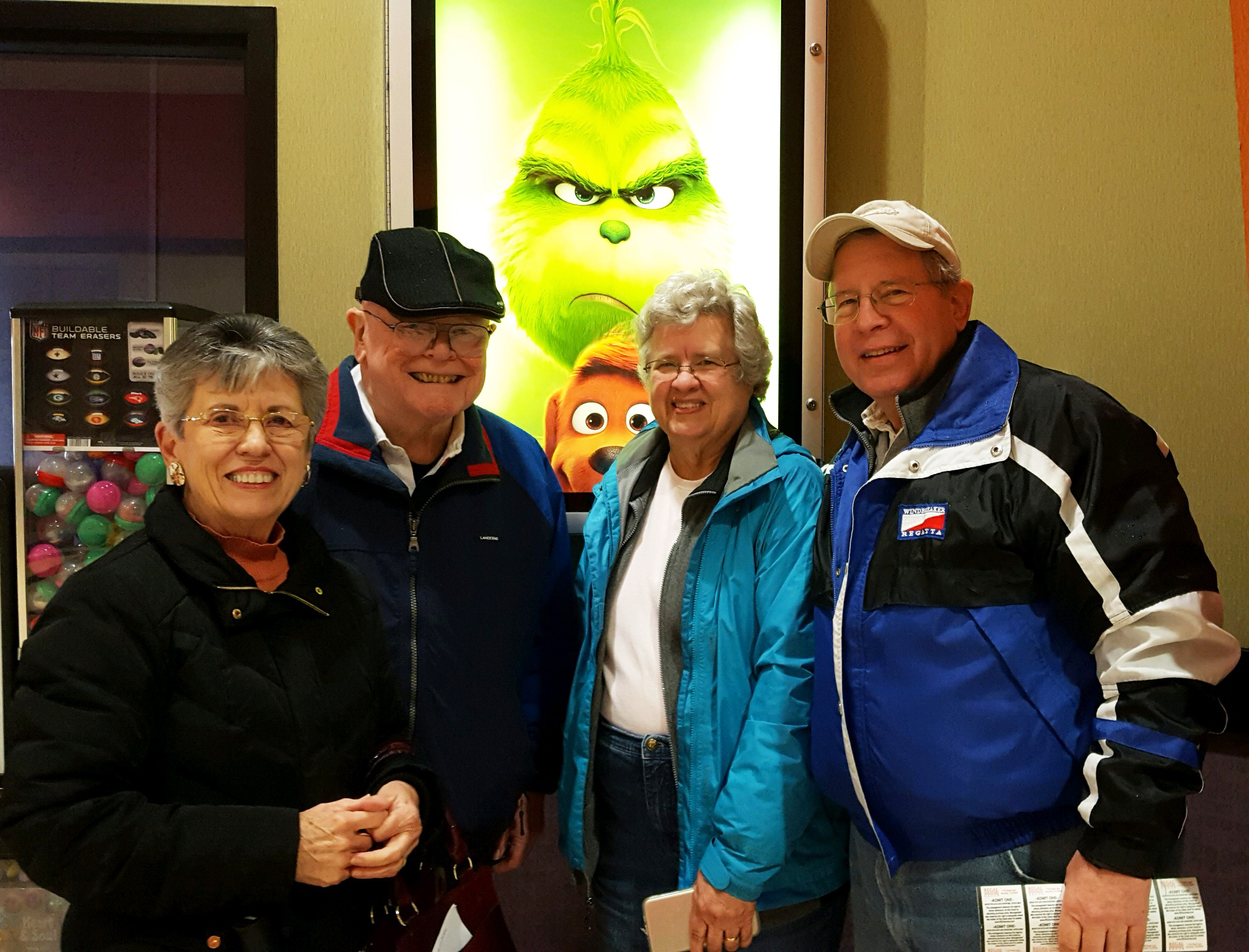 Four Cornwall Manor residents smiling in front of the movie poster for "The Grinch"