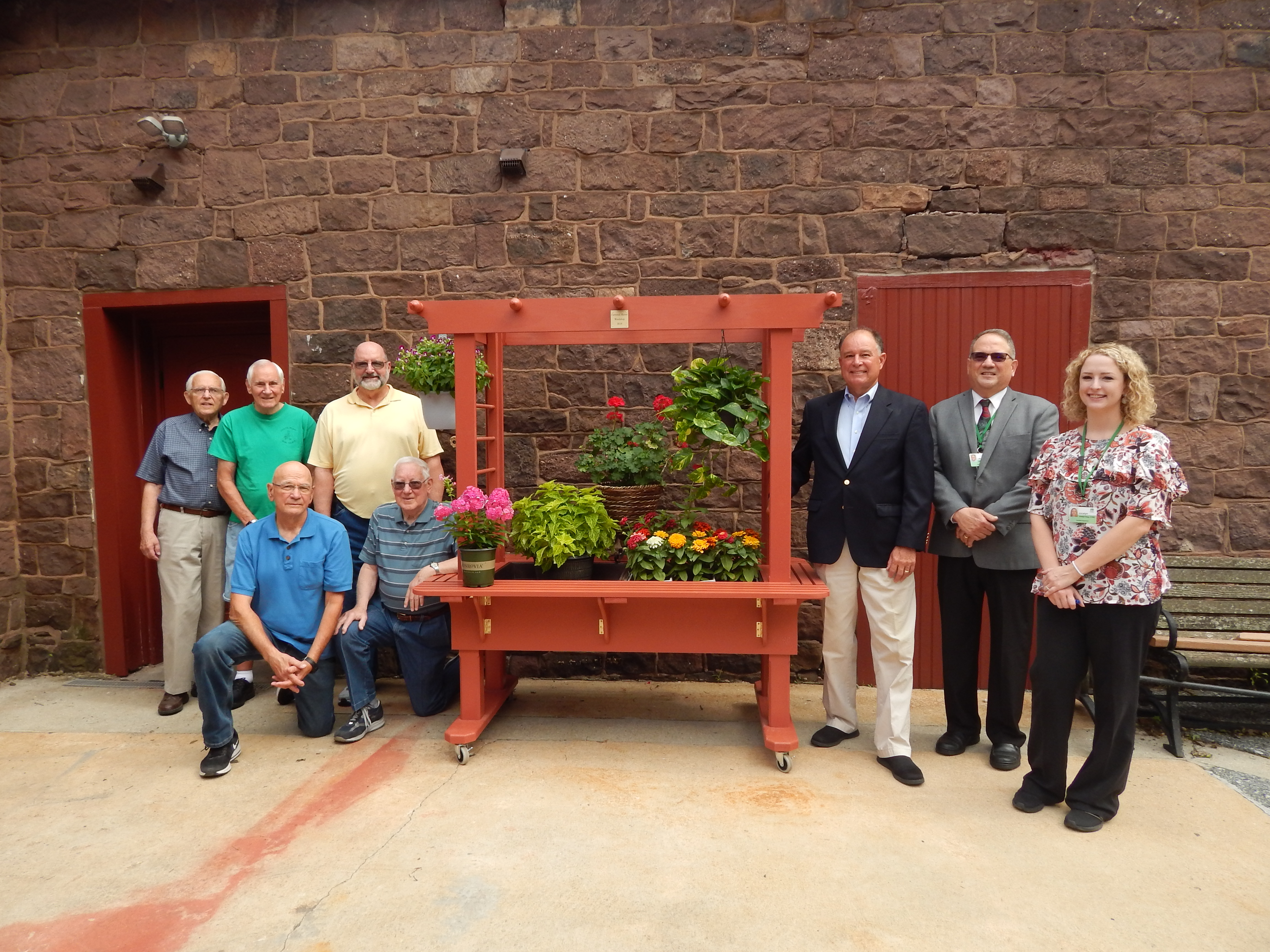 Residents and Health Center Activities Supervisor stand at gardening stations built by the Woodshop