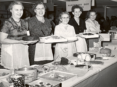 Five ladies holding various baking dishes, such as cake and donuts