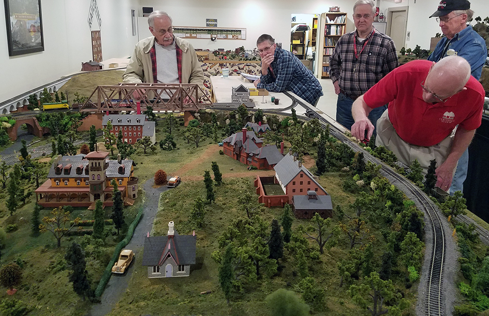 Members of the Railroad Club surrounding a model train set up